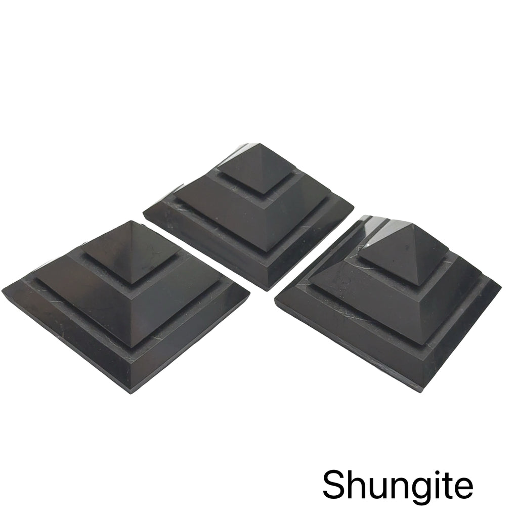 Three Extra Large Black Shungite pyramid for EMF protection and electromagnetic shielding on a white background, front view.