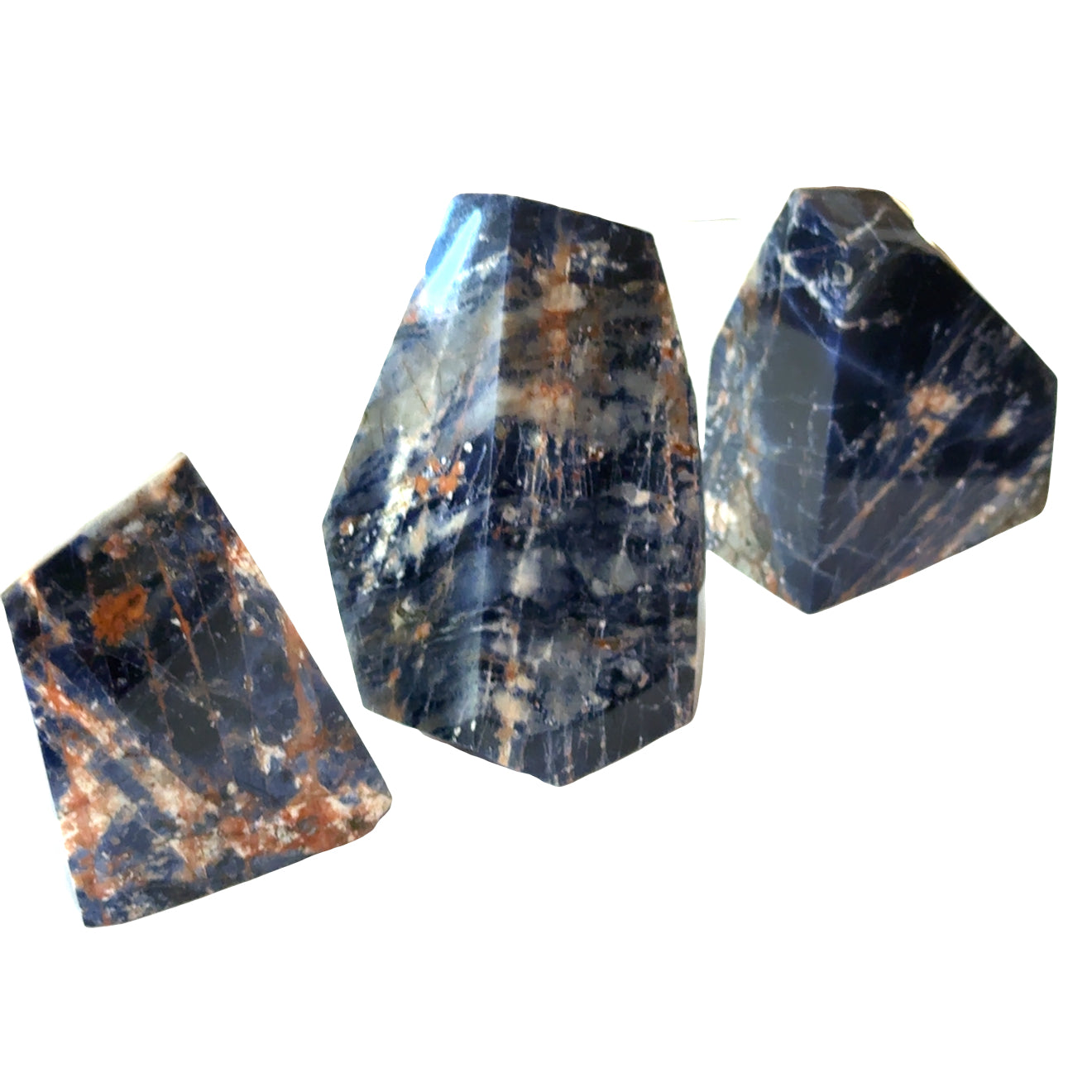 Three Orange Sodalite freeform gemstones on a white background, front view.