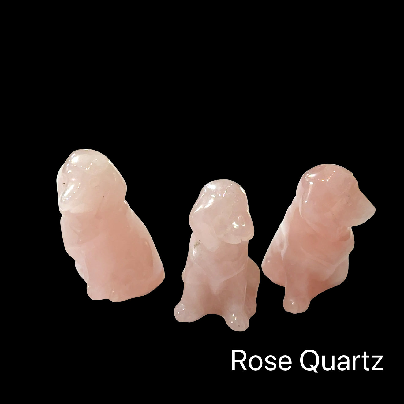 Three Rose Quartz hound Dogs gemstone carving on black background, front view.
