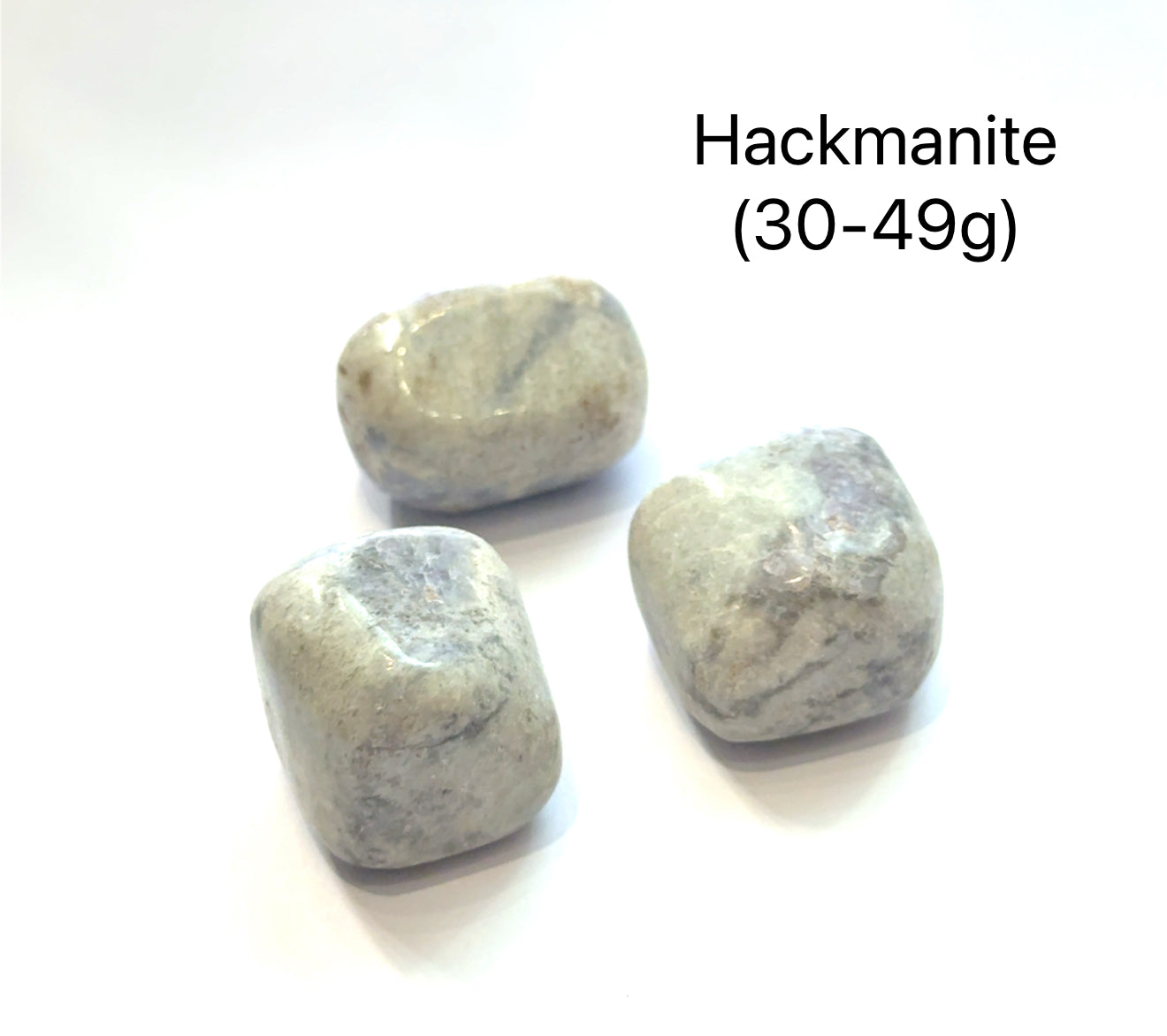 Three hackmanite stones on a white background with text indicating the weight range of (30-49g), overview.