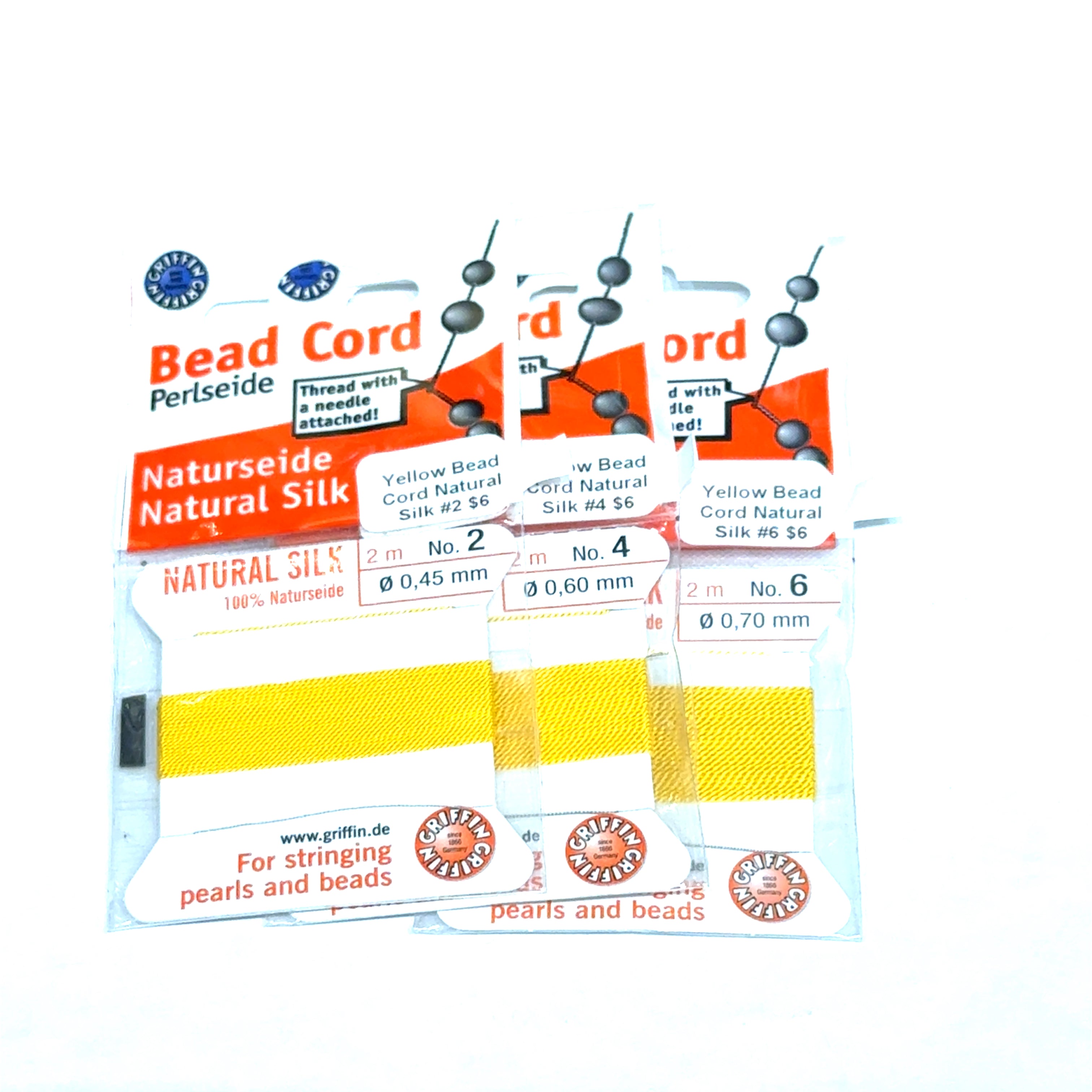 Three package of Yellow Natural Silk Bead Cord  #2,4, & 6 on a white background, front view.