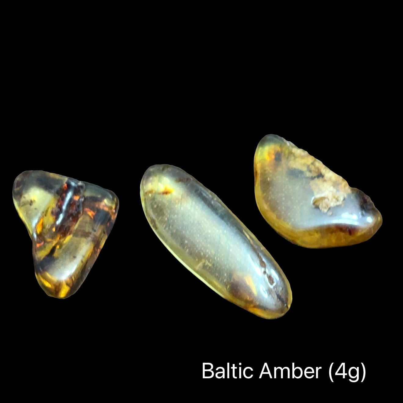 Three pieces of Baltic Amber on a black background with text indicating weight range (4g), front view.