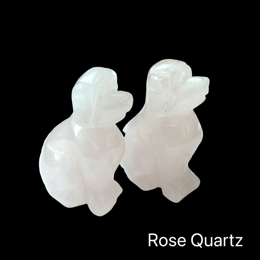 Two Rose Quartz hound Dogs gemstone carving on black background, front view.