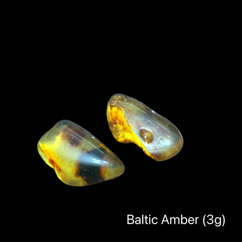 Two pieces of Baltic Amber on a black background with text indicating weight range (3g), front view