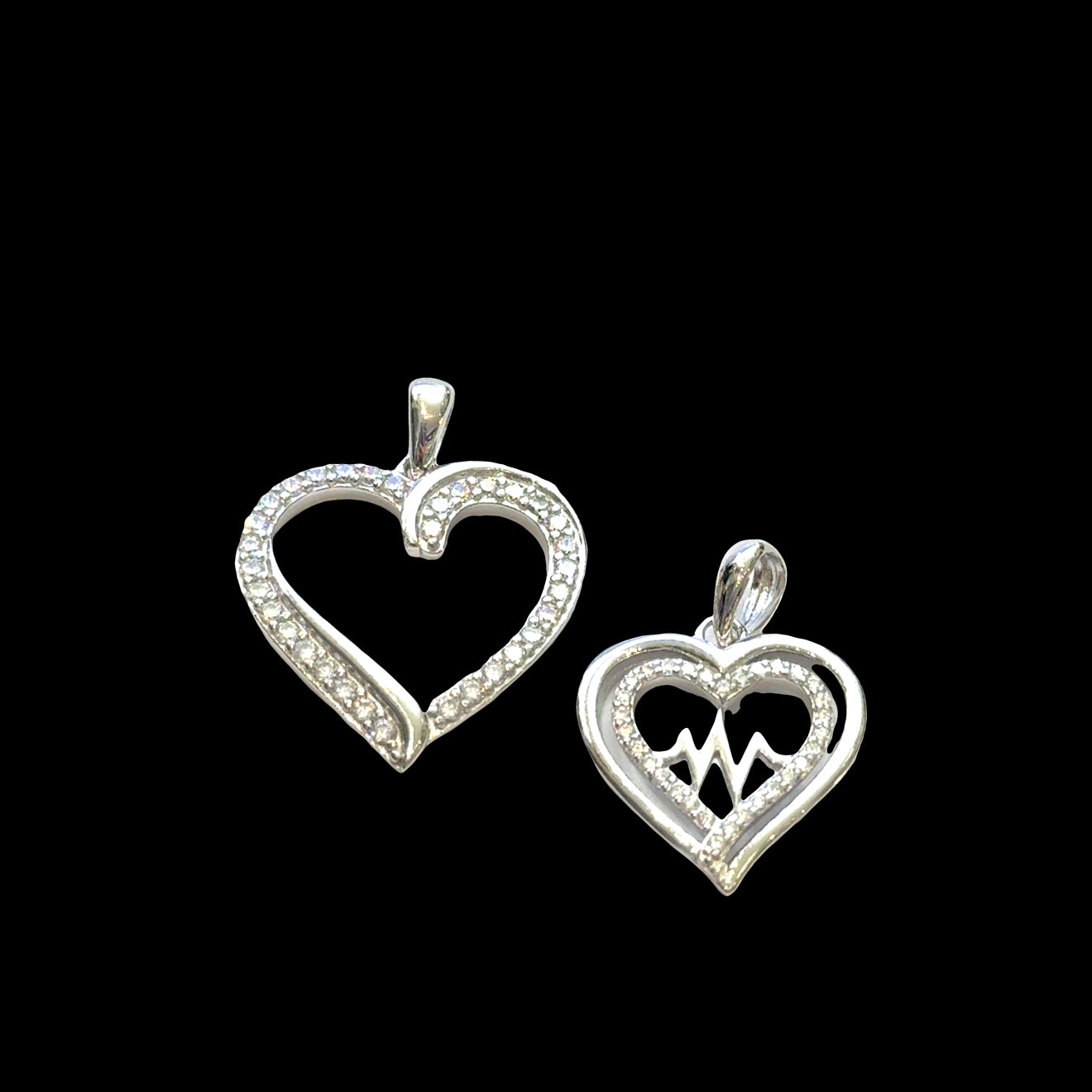 Two sterling silver heart-shaped pendants on a black background, front view.