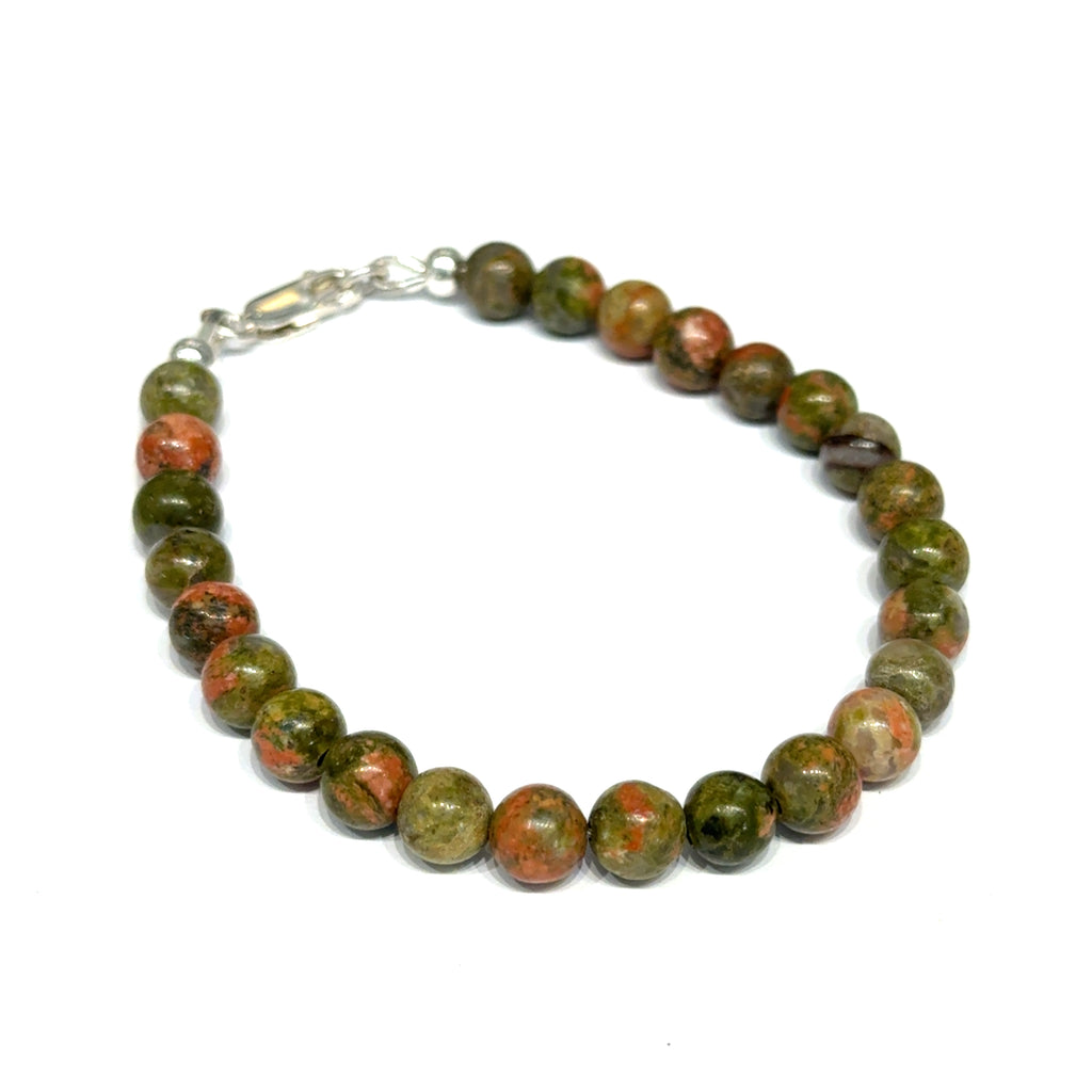 Unakite beaded bracelet with 6mm smooth round gemstones and a sterling silver lobster-claw clasp for gentle emotional healing, on a white background, right-angle close-up view. 
