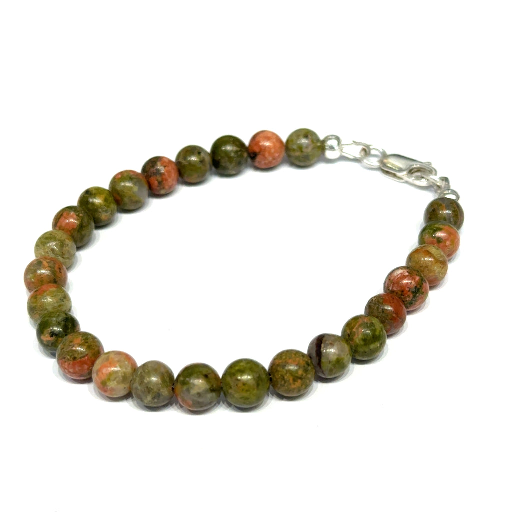 Unakite beaded bracelet with 6mm smooth round gemstones and a sterling silver lobster claw clasp for gentle emotional healing, on a white background, left-angle close-up view. 
