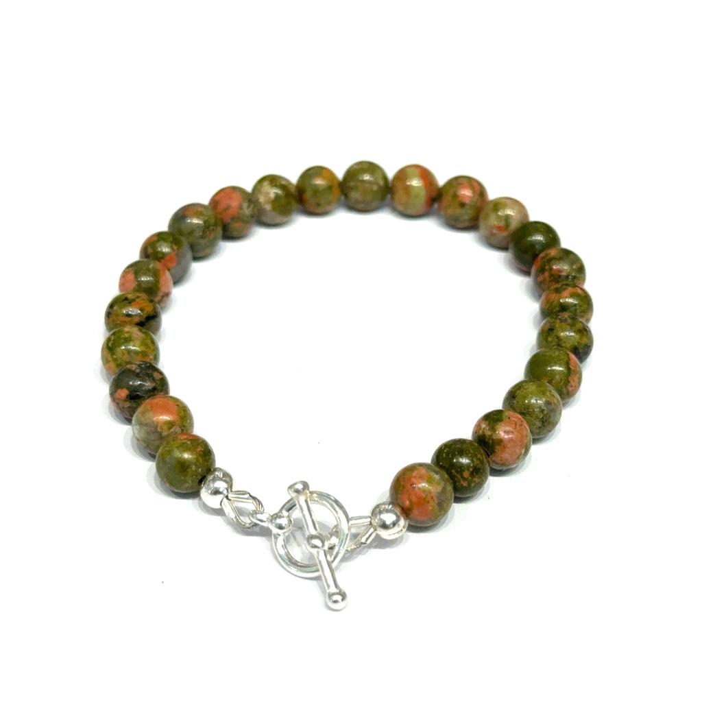 Unakite beaded bracelet with 6mm smooth round gemstones and a sterling silver toggle clasp for gentle emotional healing, on a white background, back close-up view. 