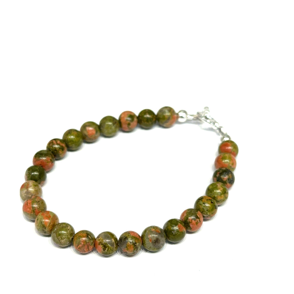 Unakite beaded bracelet with 6mm smooth round gemstones and a sterling silver toggle clasp for gentle emotional healing, on a white background, left angle close-up view. 
