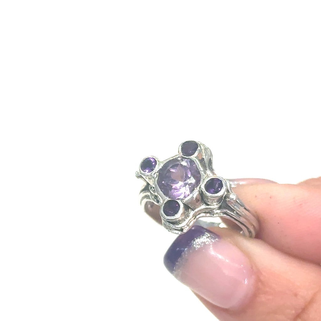 Unique Amethyst gemstone ring with bezel‑set faceted stones and stepped design on white in finger tips to show close up view