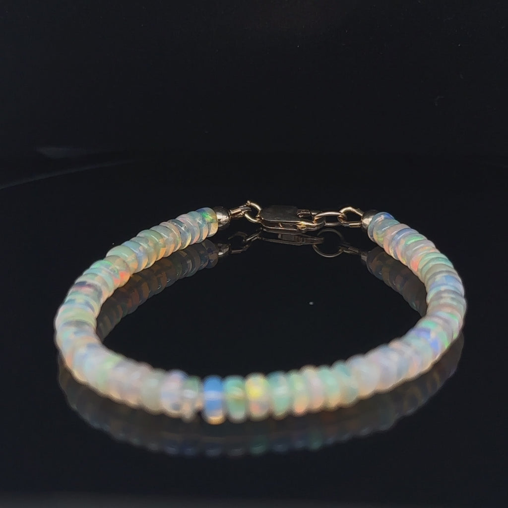 Genuine Ethiopian Opal gemstone bracelet with smooth roundel beads and gold‑filled lobster clasp on black center overview video