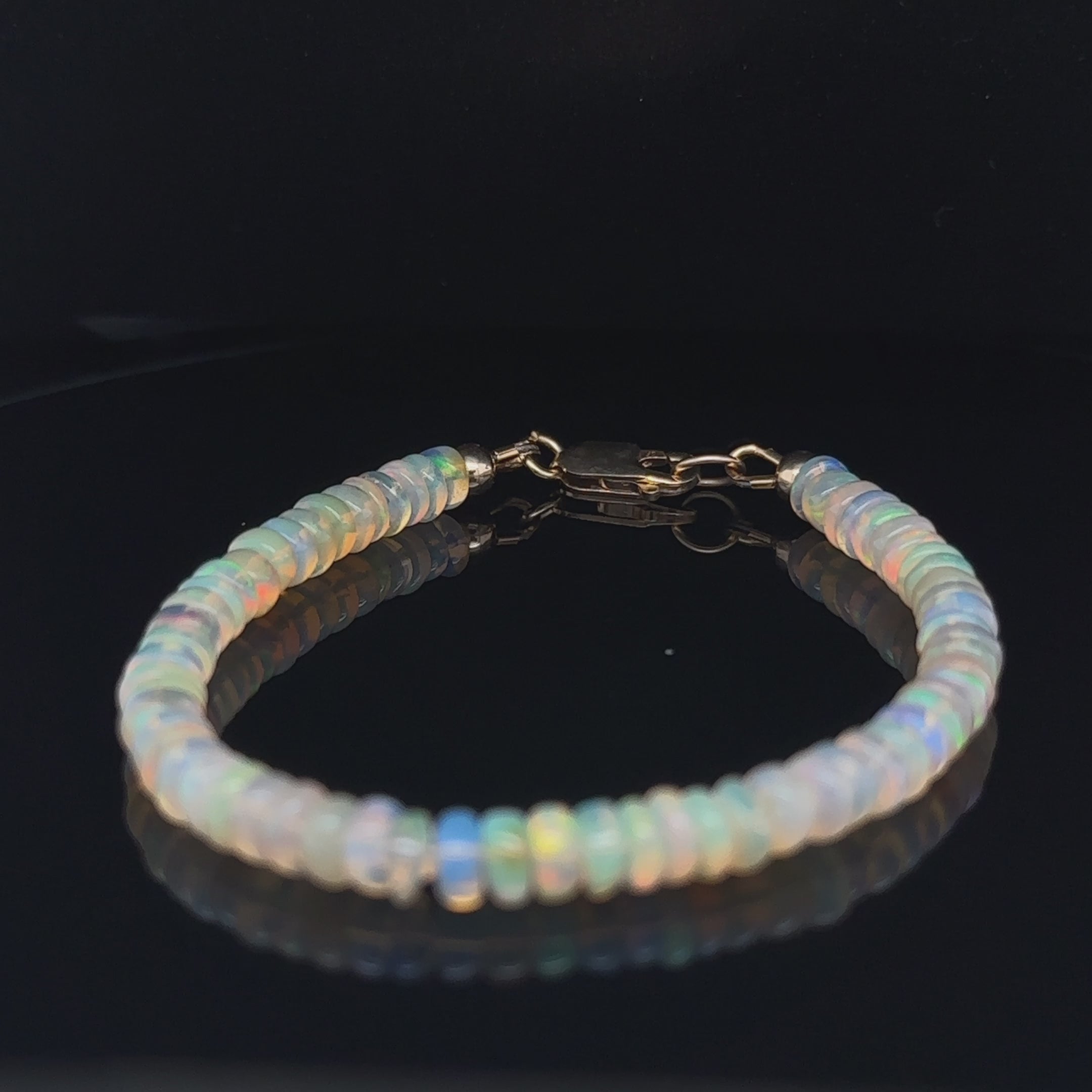 Genuine Ethiopian Opal gemstone bracelet with smooth roundel beads and gold‑filled lobster clasp on black center overview video