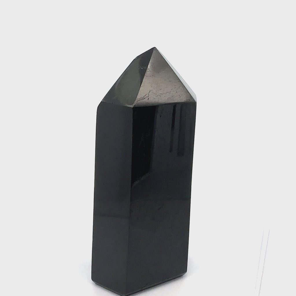 Close-up of a Black Tourmaline crystal showing natural striations and deep black luster on a white background front view video.