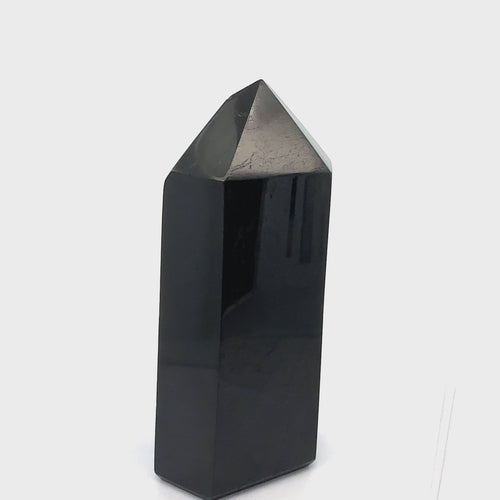 Close-up of a Black Tourmaline crystal showing natural striations and deep black luster on a white background front view video.