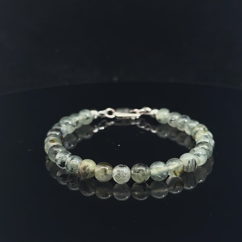 Close-up of natural prehnite beads displaying a soft green color and a smooth, polished finish, size 6.5, on a white background, video. 