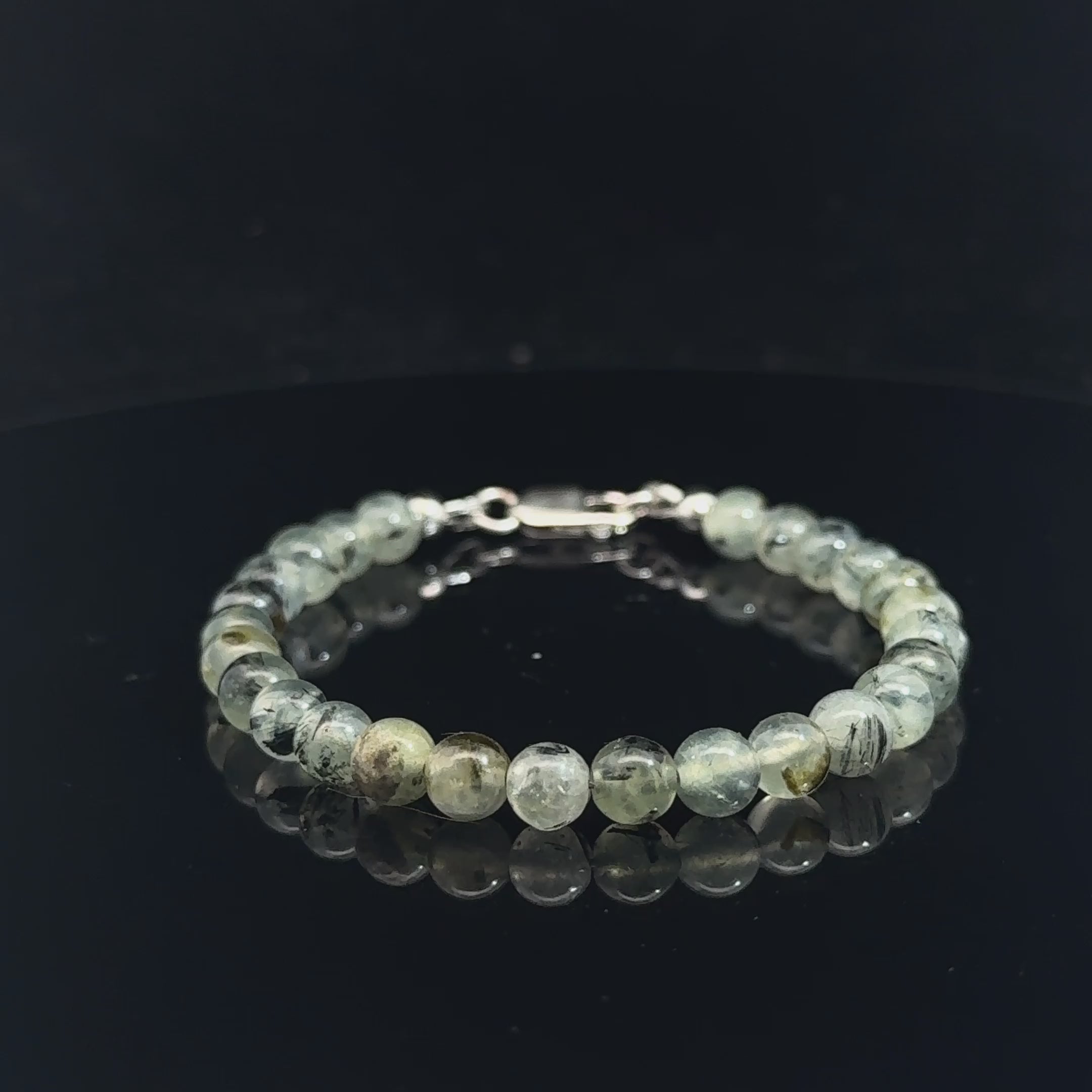 Close-up of natural prehnite beads displaying a soft green color and a smooth, polished finish, size 6.5, on a white background, video. 