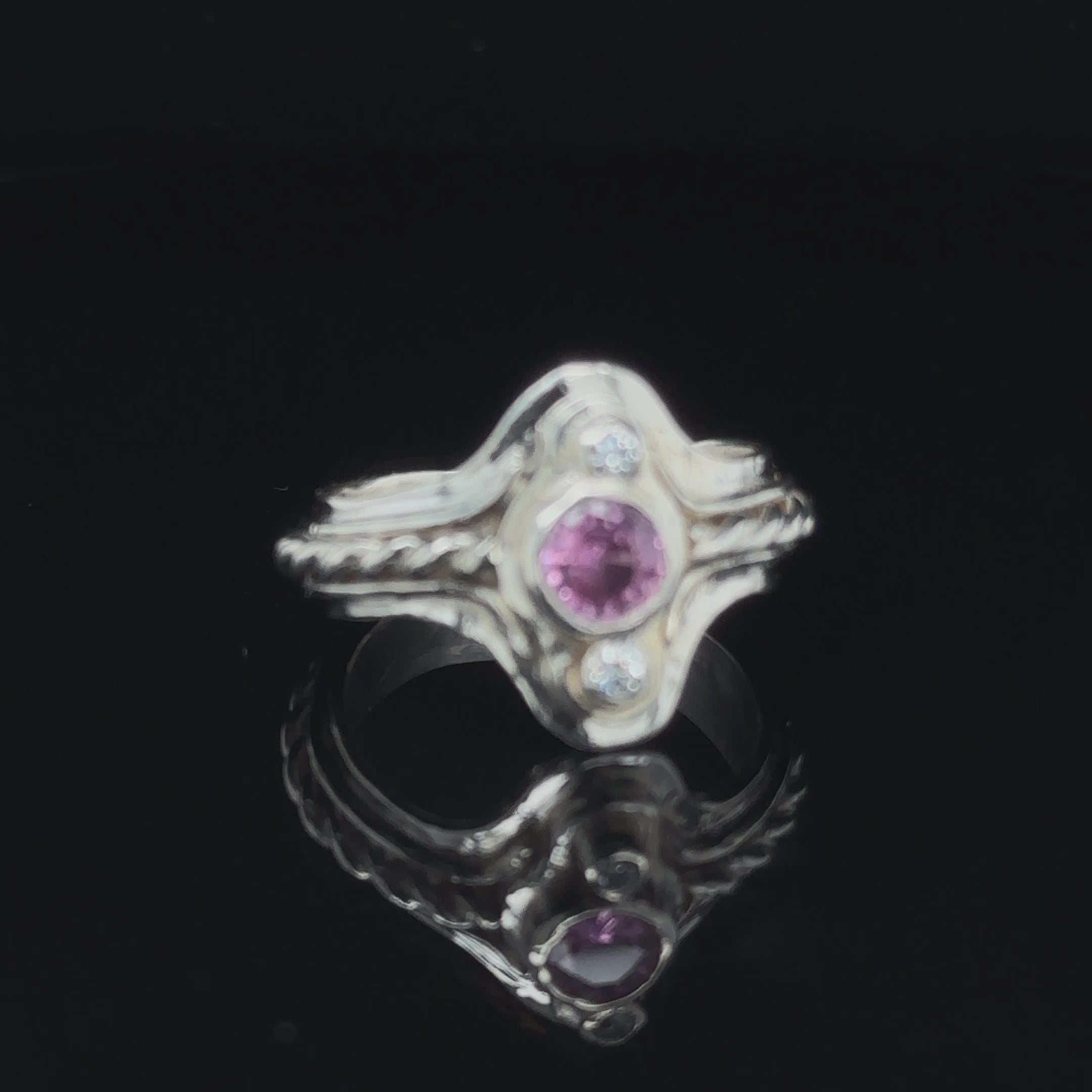 Hand‑forged sterling silver step ring with 5.4mm Pink Sapphire and two bezel‑set diamonds, size 7.5 on black close-up view video