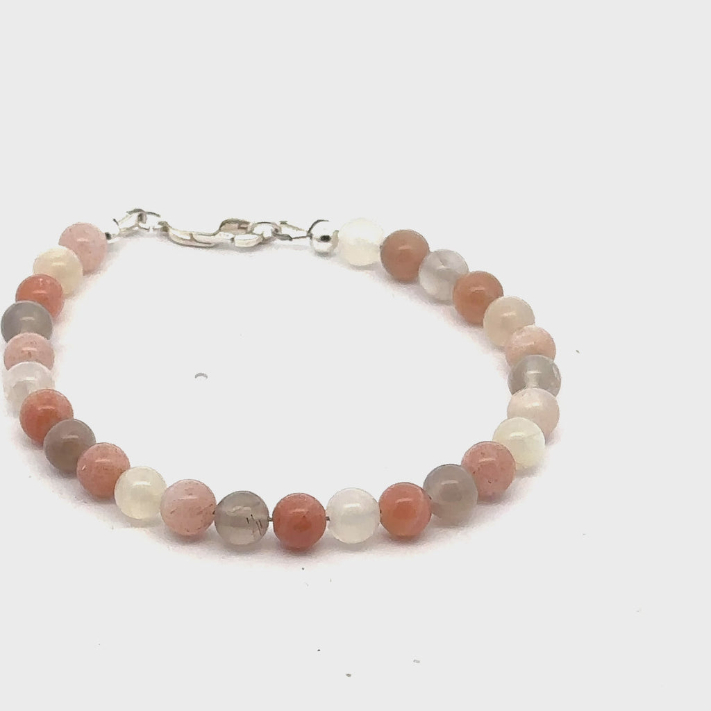 A mixed Moonstone gemstone beaded bracelet with a sterling silver lobster claw clasp on a white background, left side, overview. video