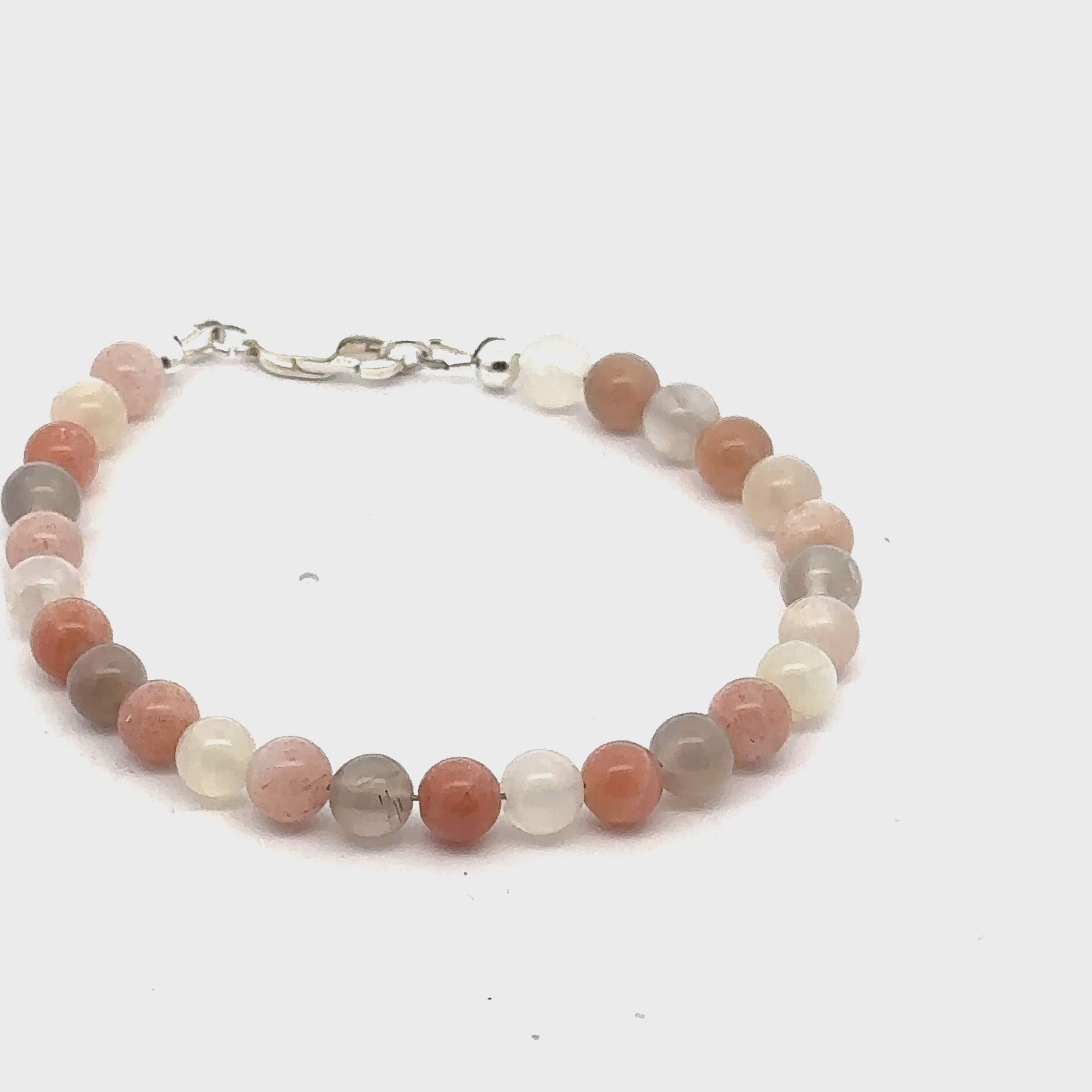 A mixed Moonstone gemstone beaded bracelet with a sterling silver lobster claw clasp on a white background, left side, overview. video