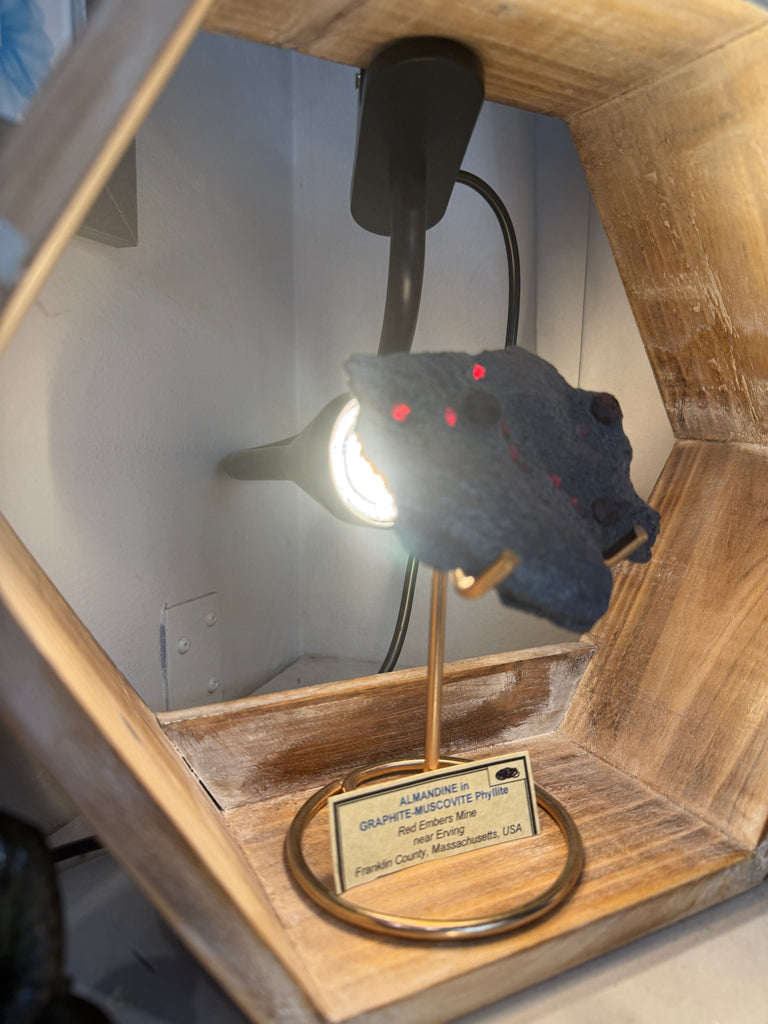 Almandine Garnet Raw Gemstone with Graphite on white displayed with stand and information card lit up side view