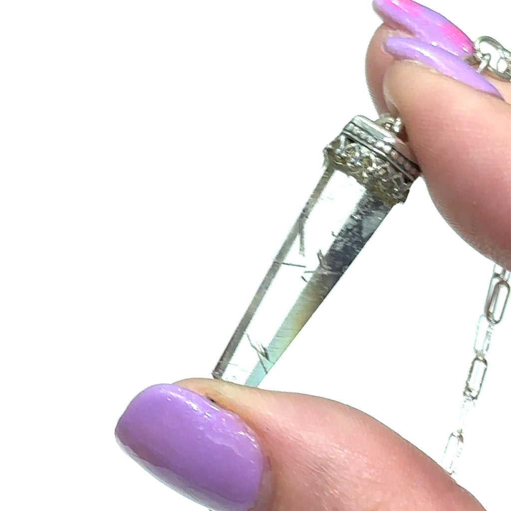 #1 Close-up of golden needle inclusions in Rutilated Quartz gemstone pendant in models finger tips on white background close up view.