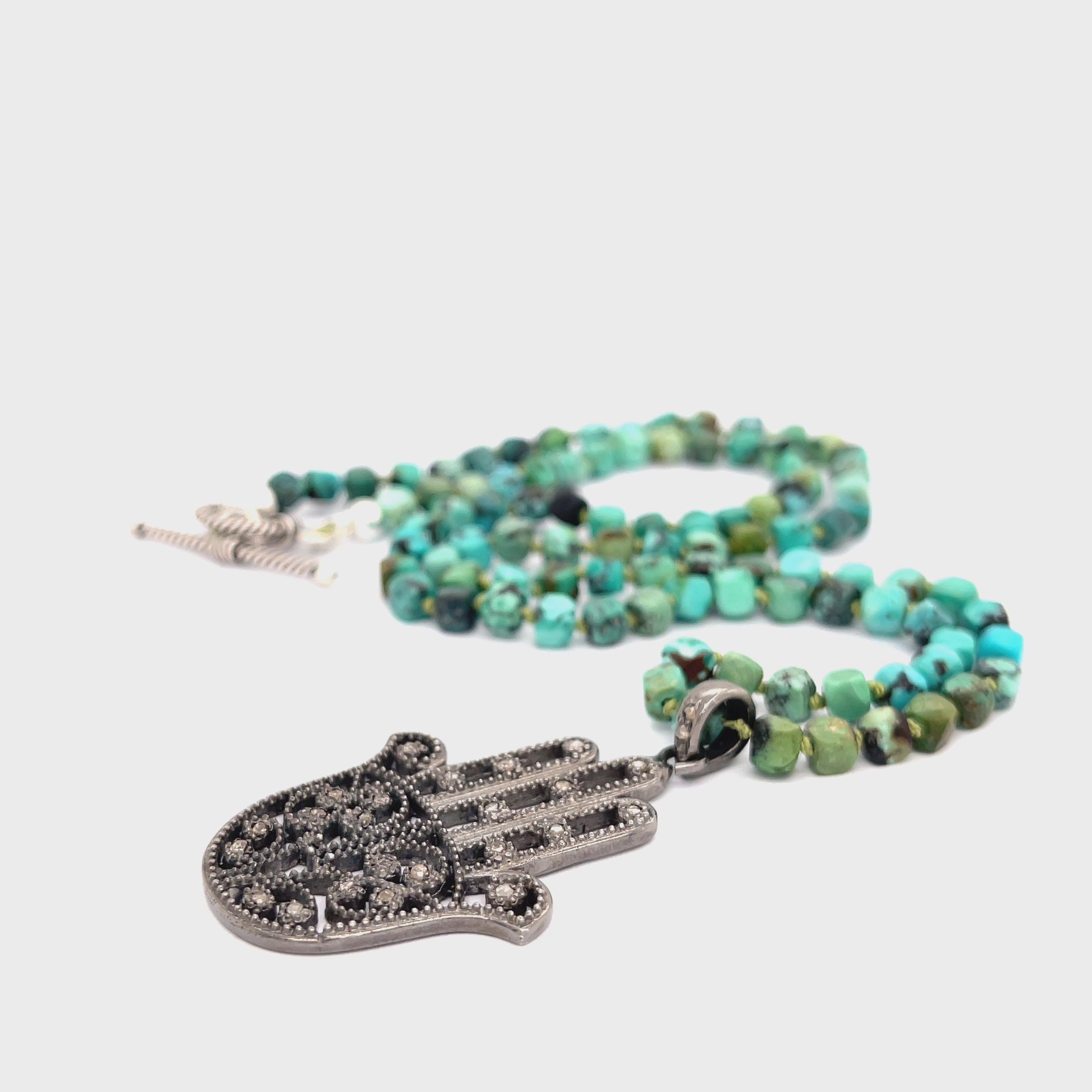 Turquoise gemstone knotted necklace with pave diamond Humza pendant handcrafted by Hidden Jewel of the South End n a white background center  overview video