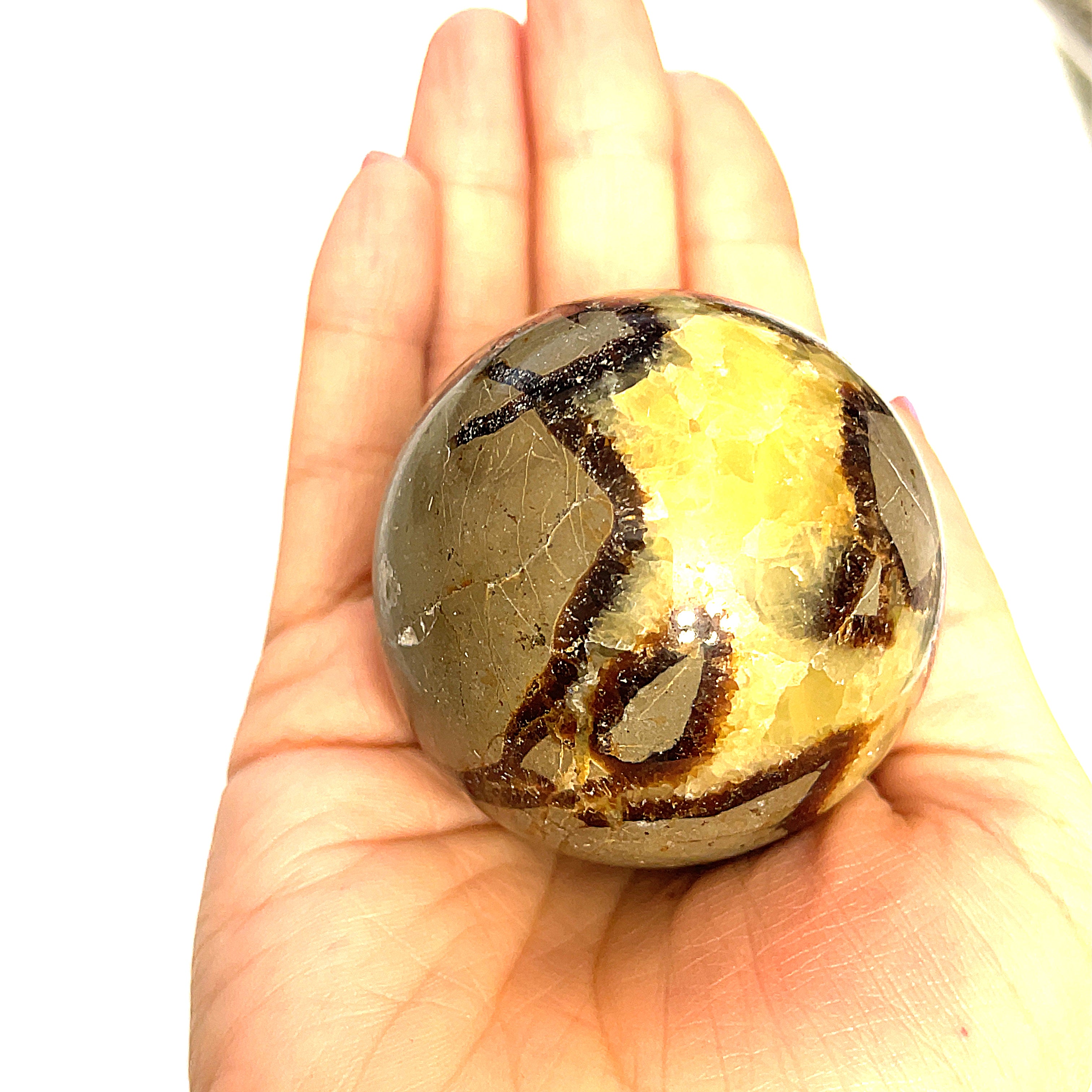 #2 A gemstone sphere displayed in a model's palm on a white background in front view.