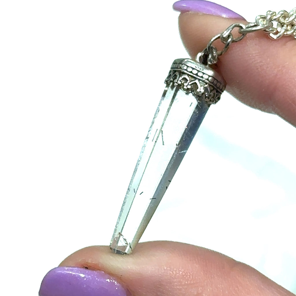 #2 Close-up of golden needle inclusions in Rutilated Quartz gemstone pendant in models finger tips on white background close up view.