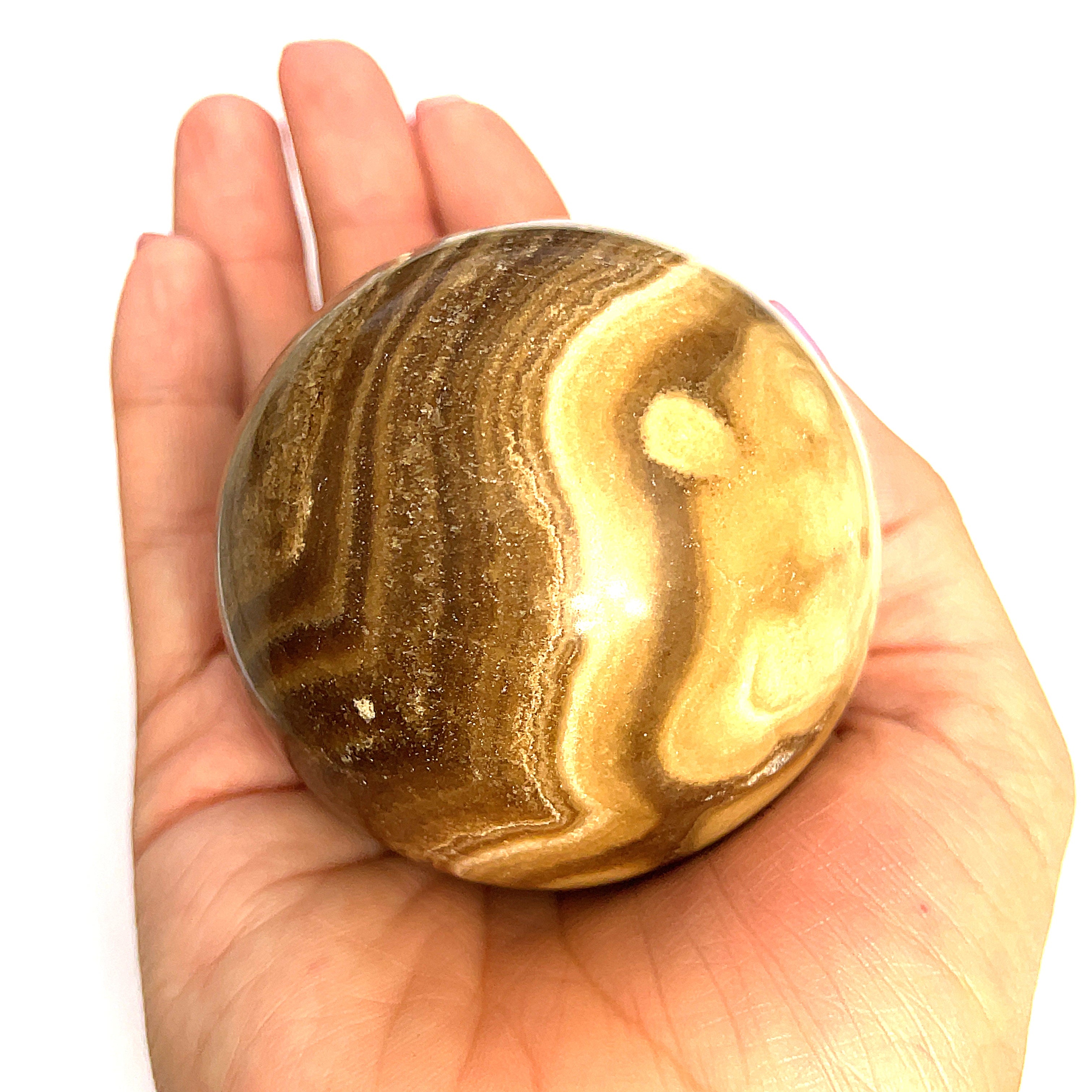 #2 Close-up of polished Chocolate Calcite sphere on a models hand for a close up, front, overview.
