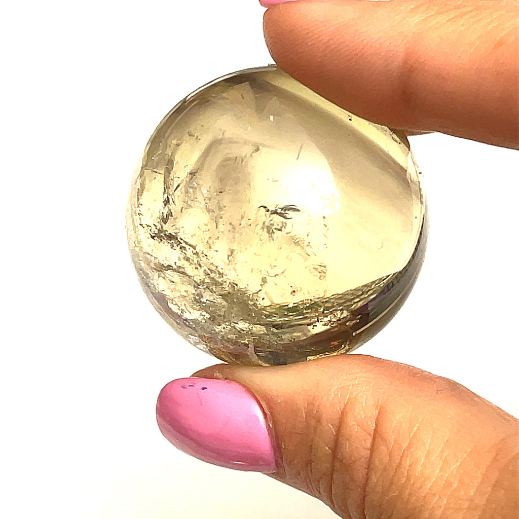 #2 one  citrine gemstone sphere in the models finger tips on a white background for a close up view.