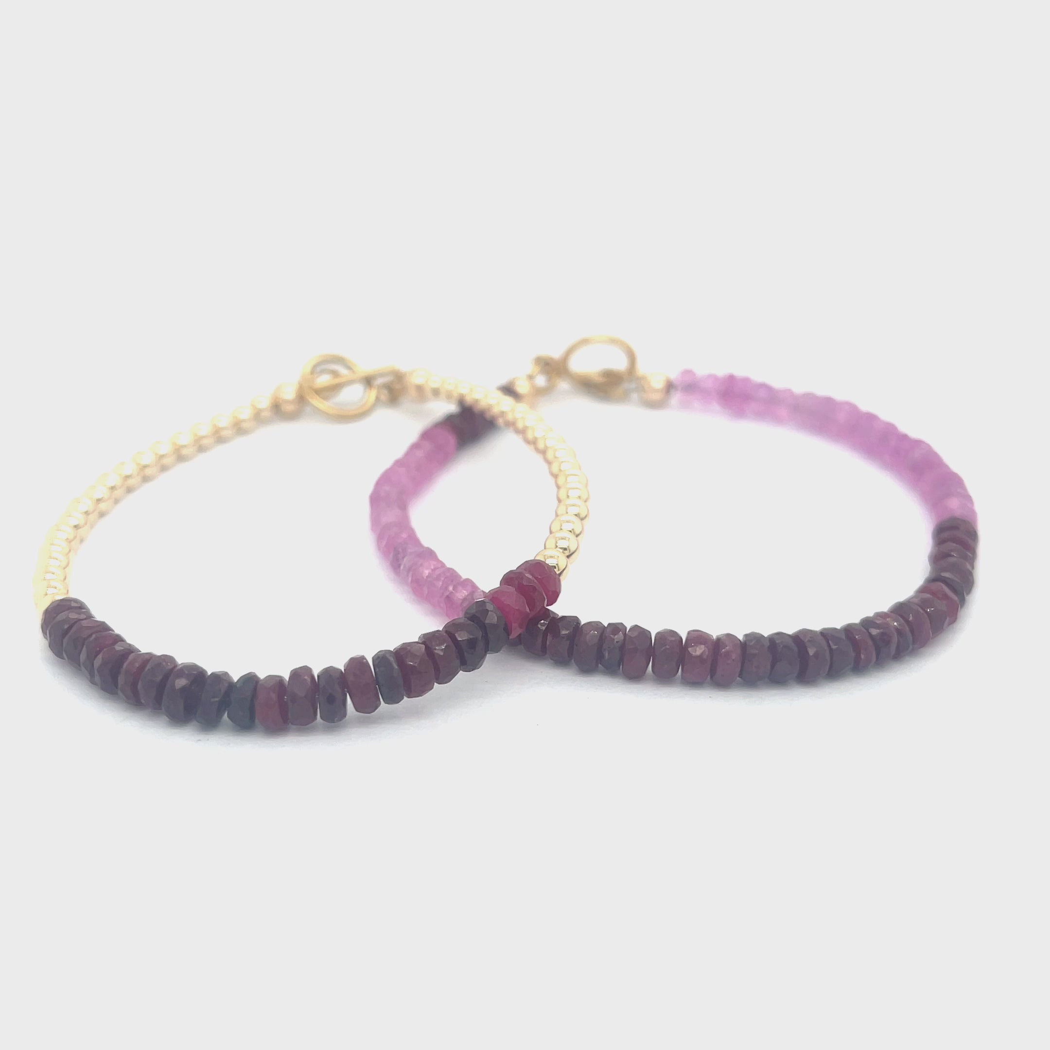 Two genuine ruby gemstone beaded bracelets with gold-filled toggle clasps, featuring faceted roundel rubies ranging in color from purple to red, on a white background front overview video