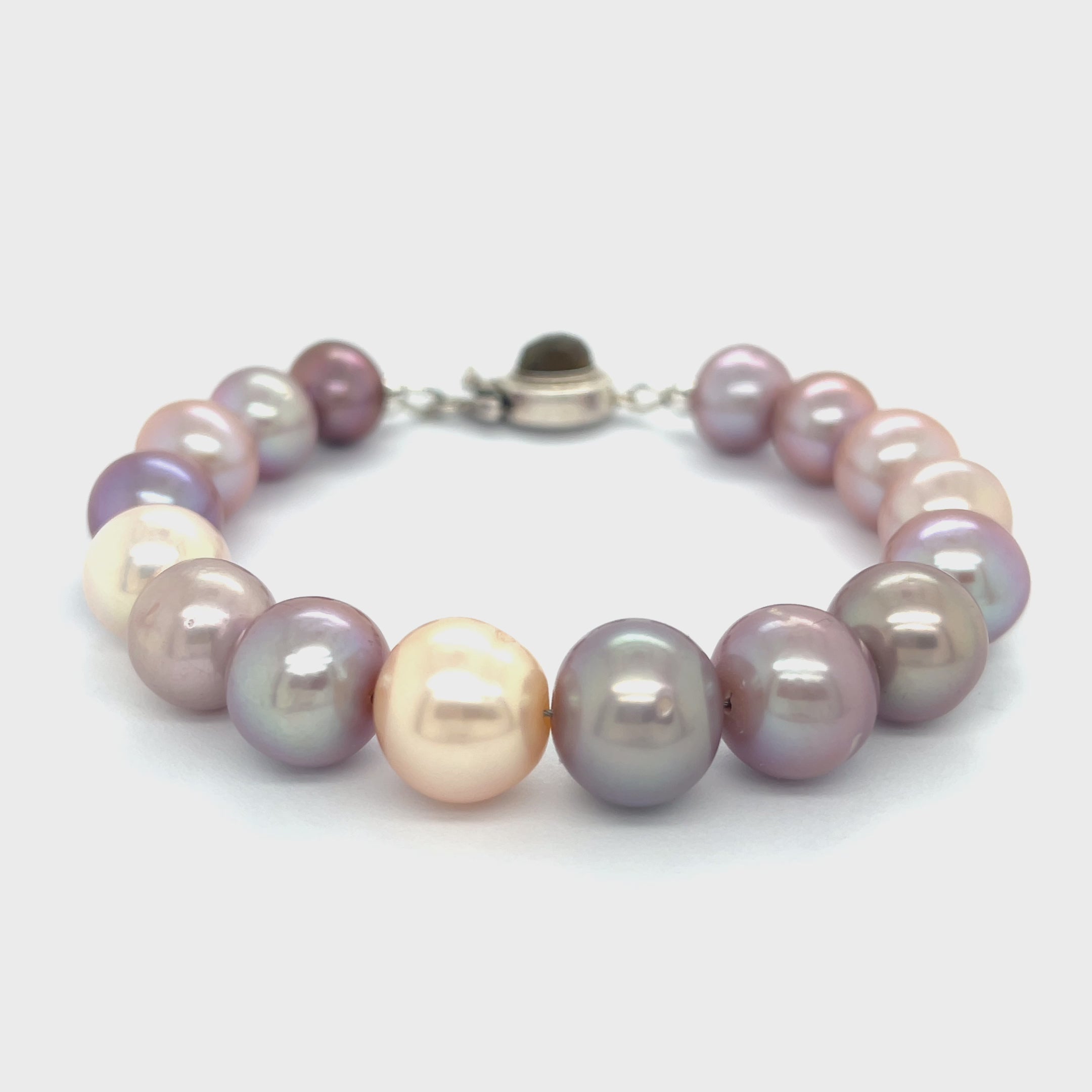 A bracelet made of Edison pearls, featuring a mix of pearl and peal beads, with a sterling silver box clasp and a bezel set labradorite gemstone on a white background, front view video.
