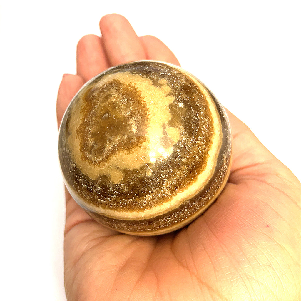 #3 Close-up of polished Chocolate Calcite sphere on a models hand for a close up, front, overview.