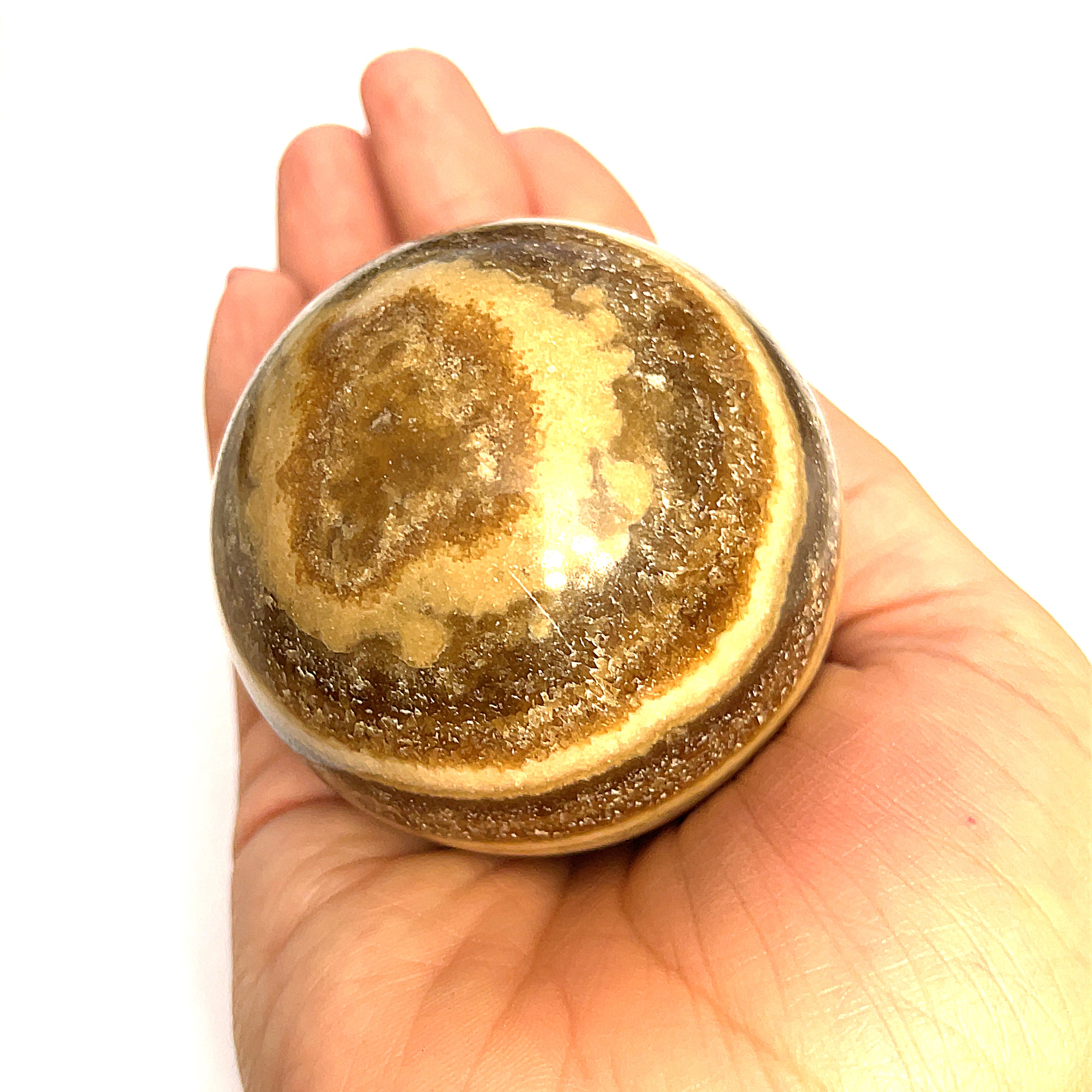 #3 Close-up of polished Chocolate Calcite sphere on a models hand for a close up, front, overview.