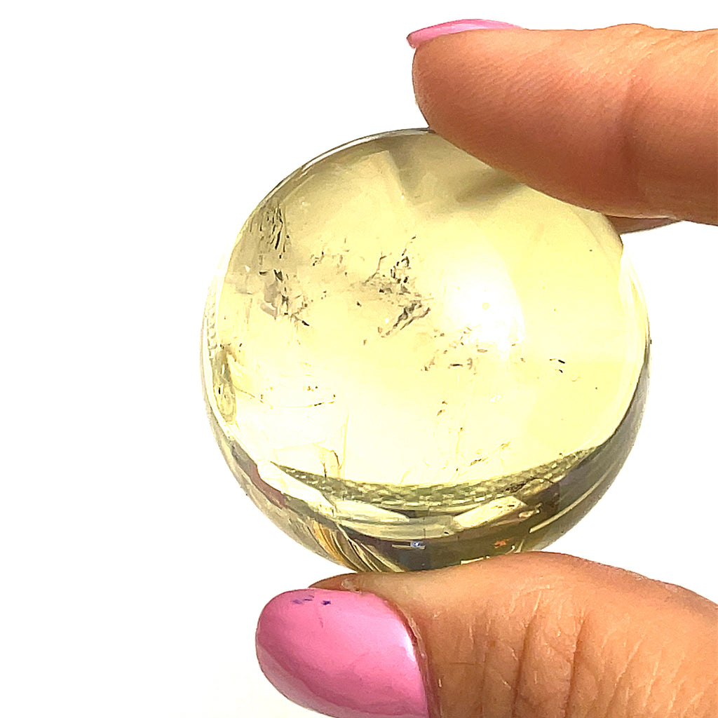 #3 one  citrine gemstone sphere in the models finger tips on a white background for a close up view.
