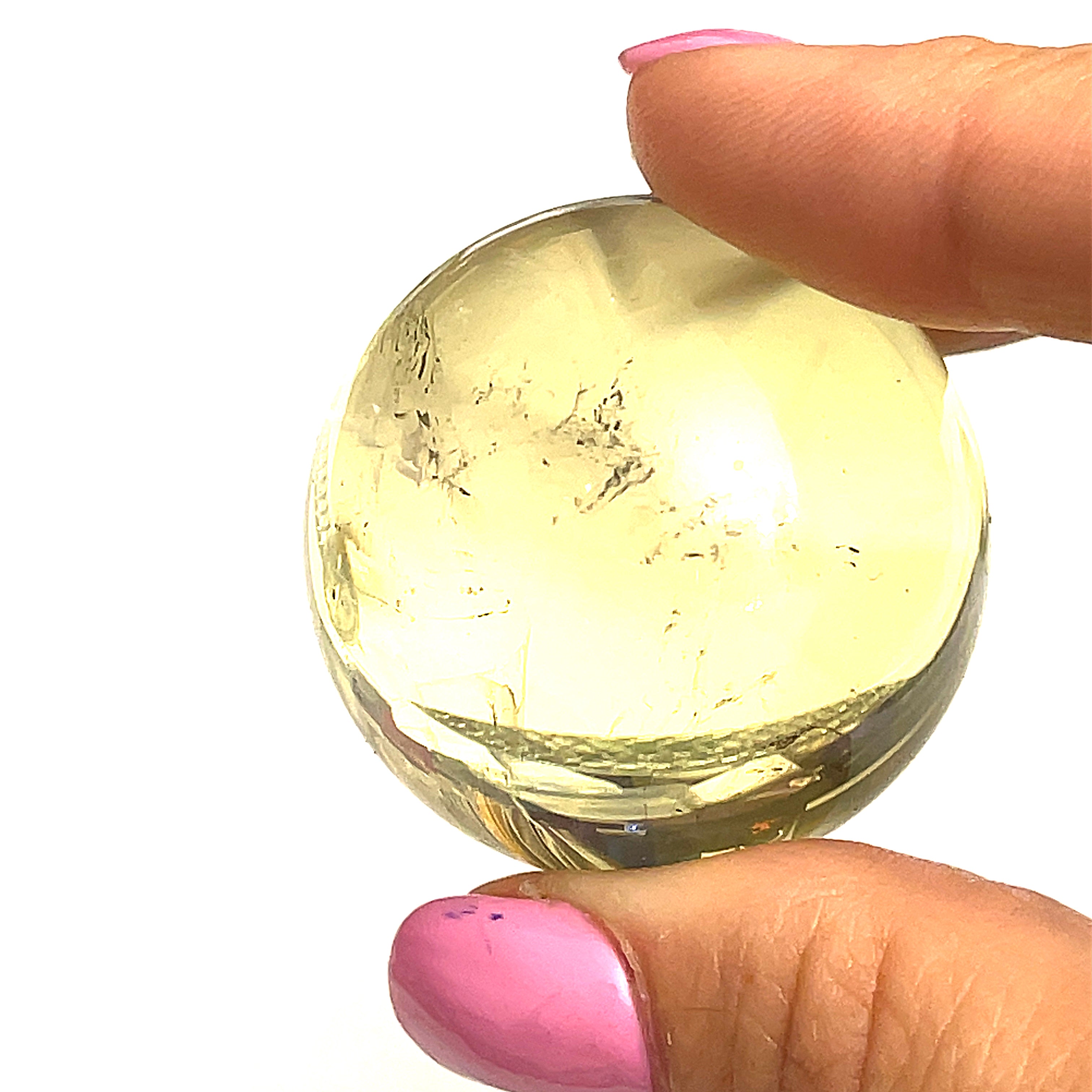 #3 one  citrine gemstone sphere in the models finger tips on a white background for a close up view.