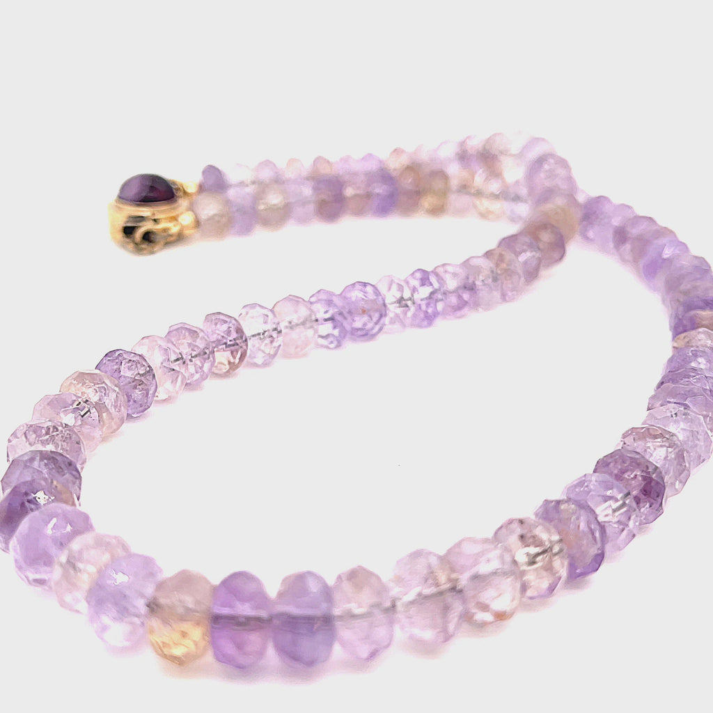 A purple ametrine beaded gemstone necklace with a gold-filled fluorite box clasp in a long, overview on a white background. video