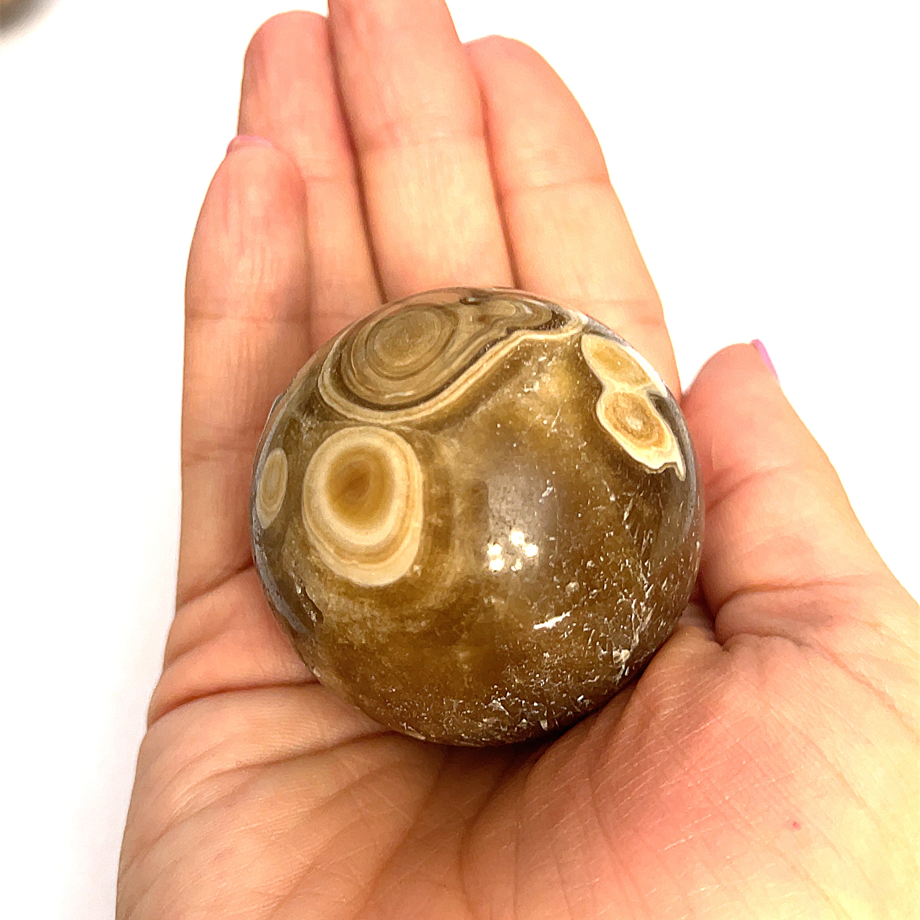 #4 Close-up of polished Chocolate Calcite sphere on a models hand for a close up, front, overview.