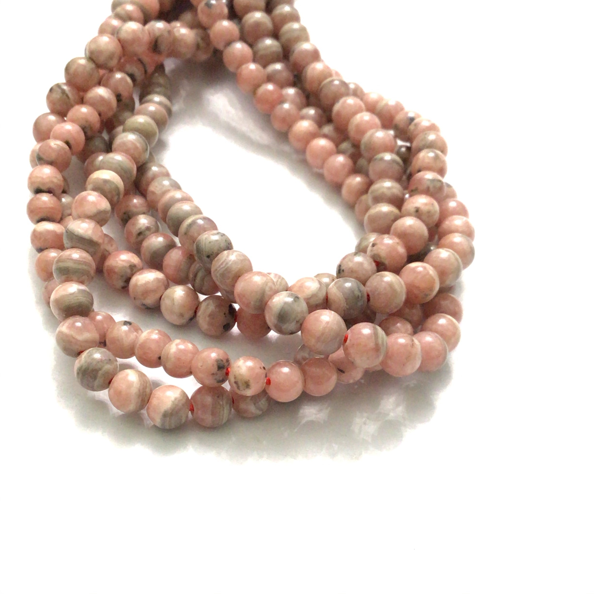 4mm Rhodochrosite smooth round gemstone strand on a white background, front overview.