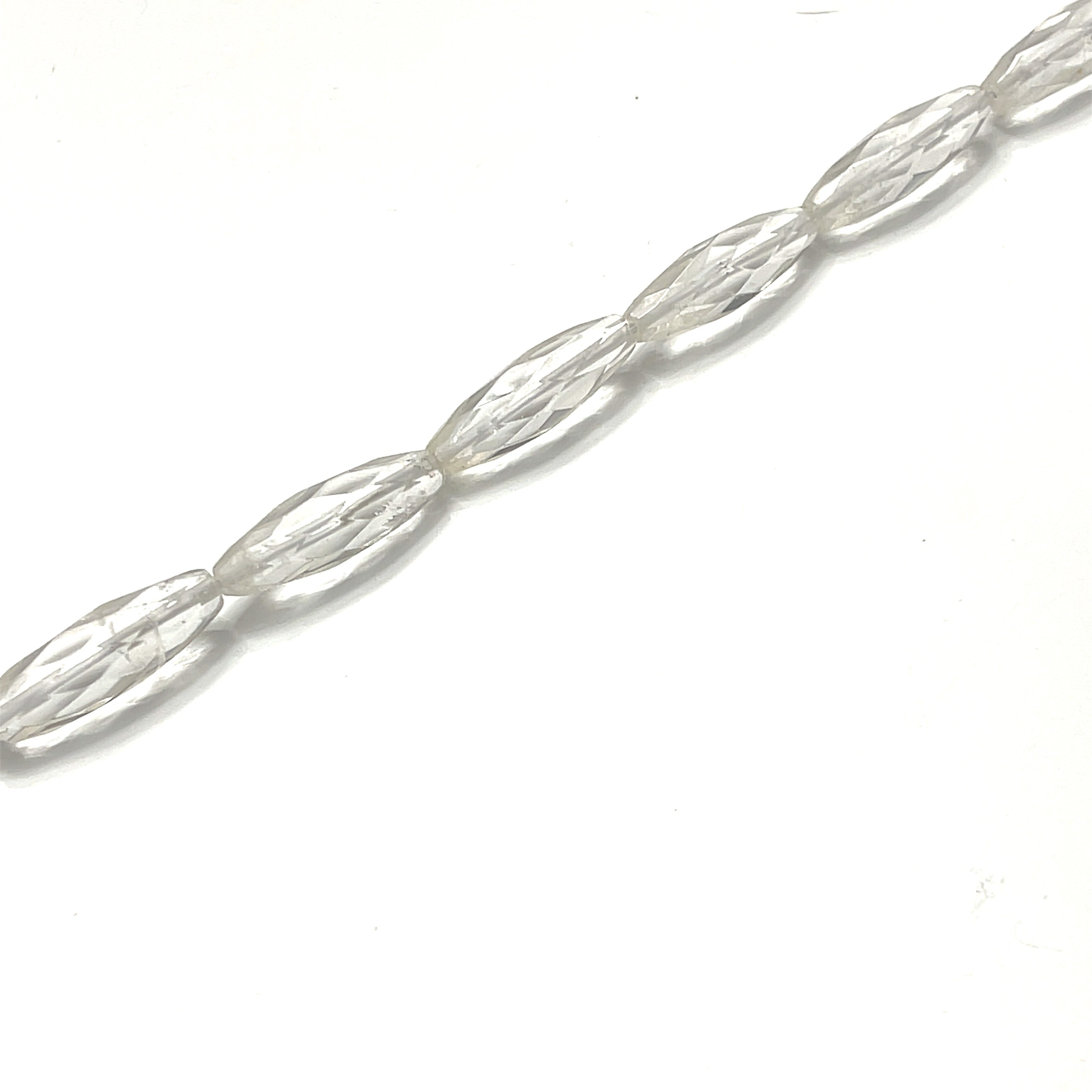 4x11mm Clear Quartz gemstone faceted barrel 8'' strand on a white background, overview. 