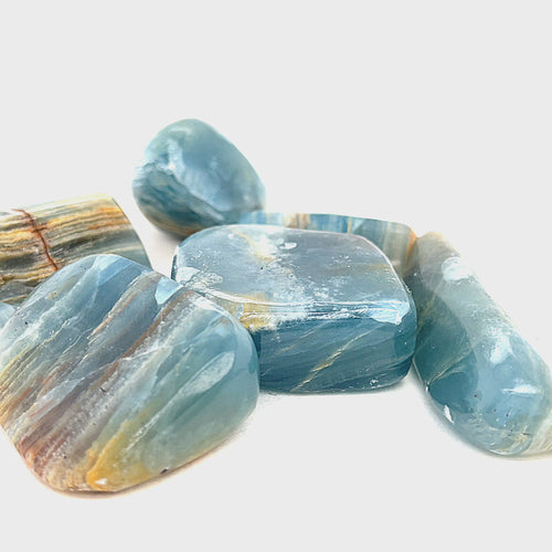 A collection of Blue Onyx gemstone with a striped pattern on a white background, front view. video