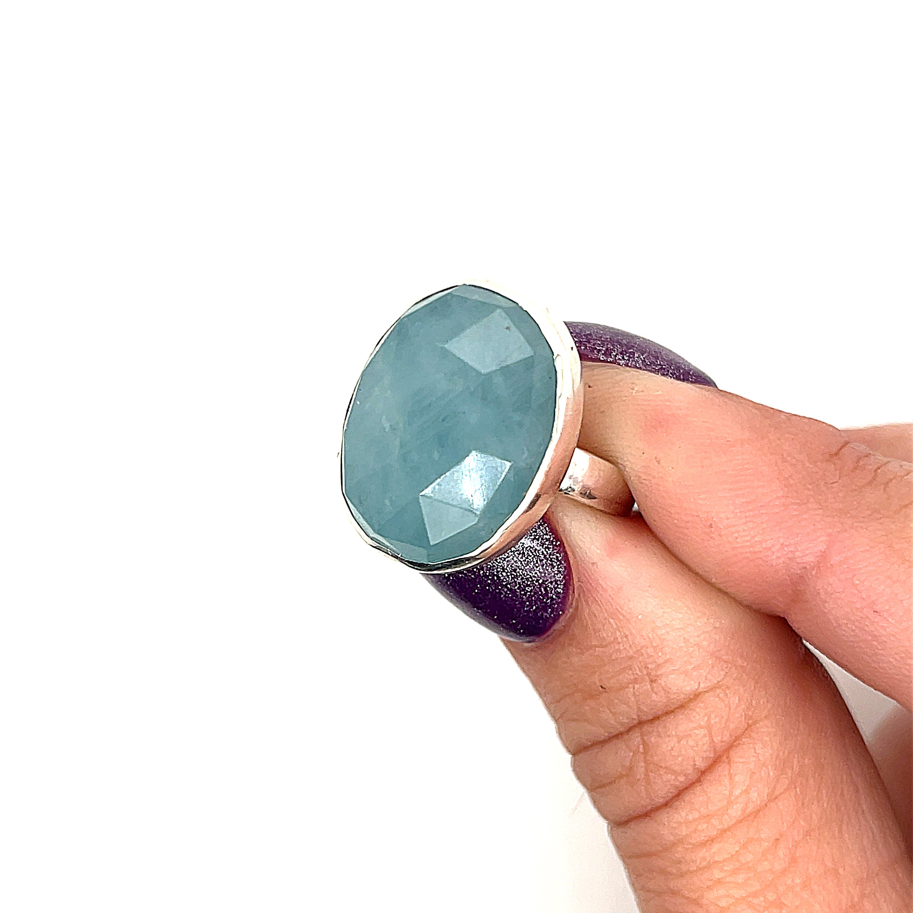 6ct faceted Aquamarine sterling silver ring — March birthstone jewelry in a models finger tips  on a white background front view. 