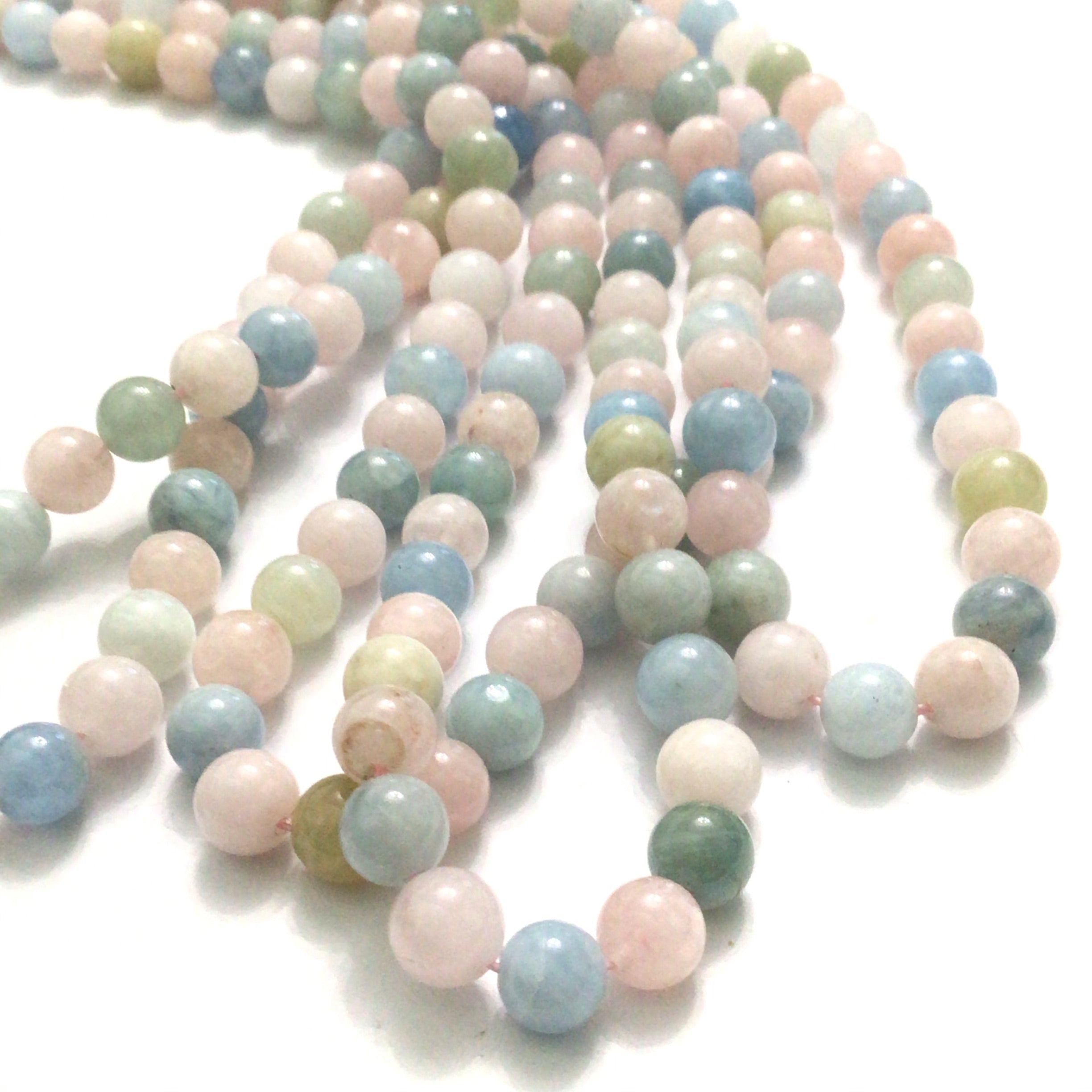6mm Morganite gemstone strand with soft pink, blue, and  peach hues round smooth 16'' strands  on a white background, front overview.
