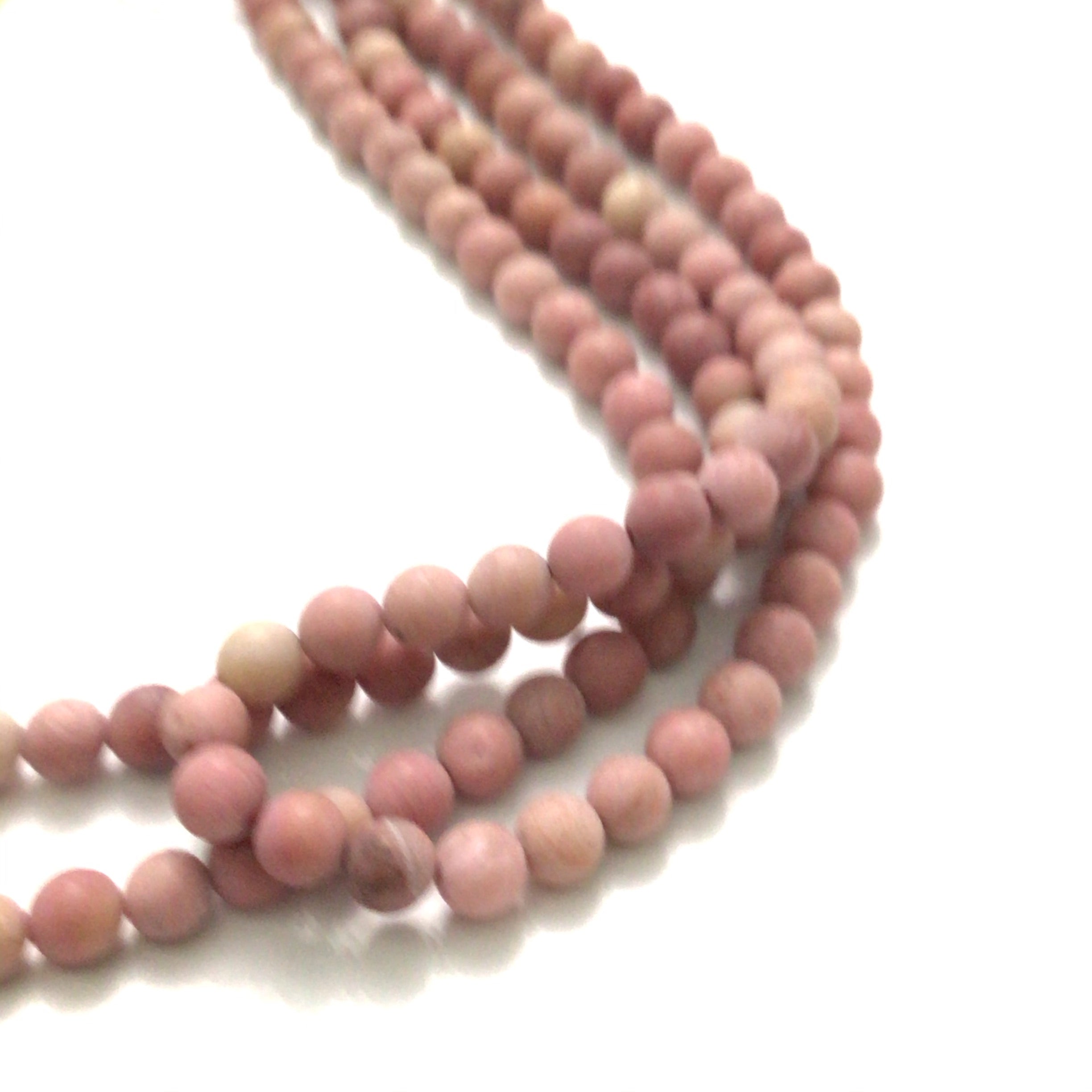 6mm Rhodonite smooth round matte gemstone strands, front overview. 