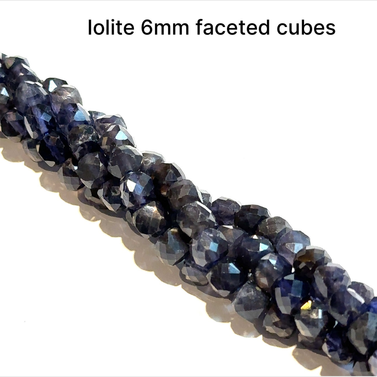 6mm faceted cubes Natural iolite gemstone strand in deep blue for third eye chakra activation and intuition on a white background, front over view. 