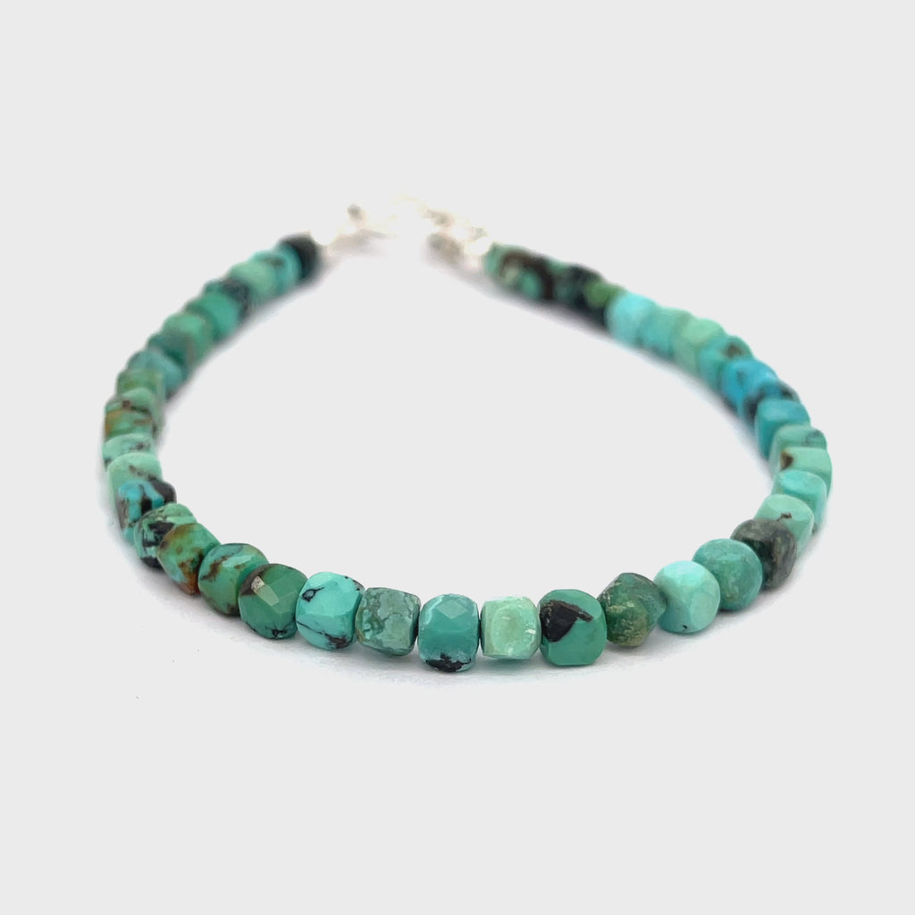 Top-grade Turquoise faceted cubed  beads strung on durable Beadalon wire with a sterling silver toggle on a white background  back view.  video