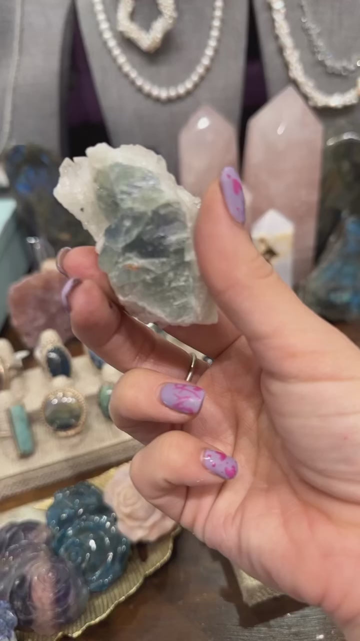 Hand holding Calcite over Fluorite with Pyrite crystal cluster in natural light on white background front view second video