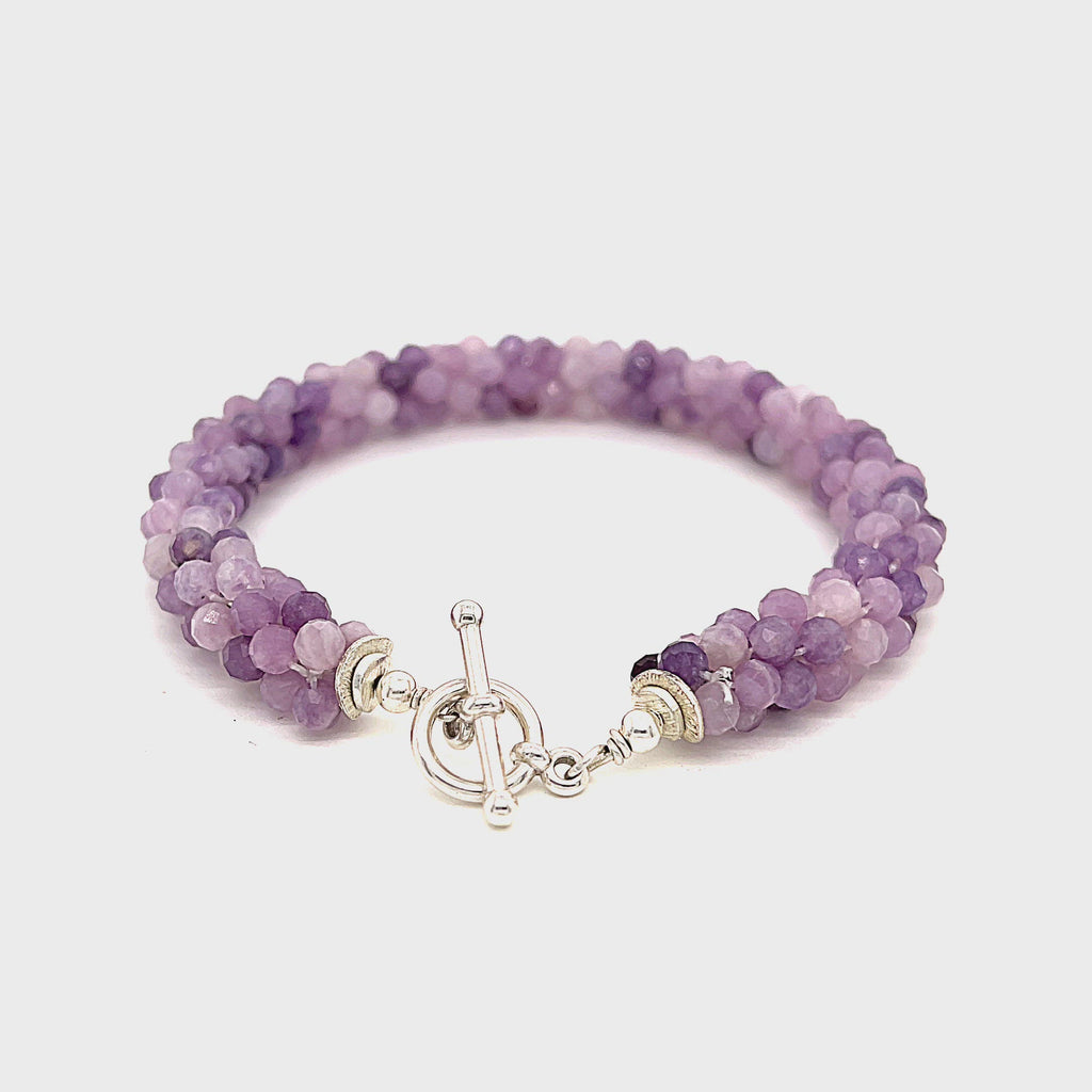 A purple sugilite gemstone bracelet with a sterling silver simple circle toggle, crocheted into a tubular pattern on a white background, toggle overview. video