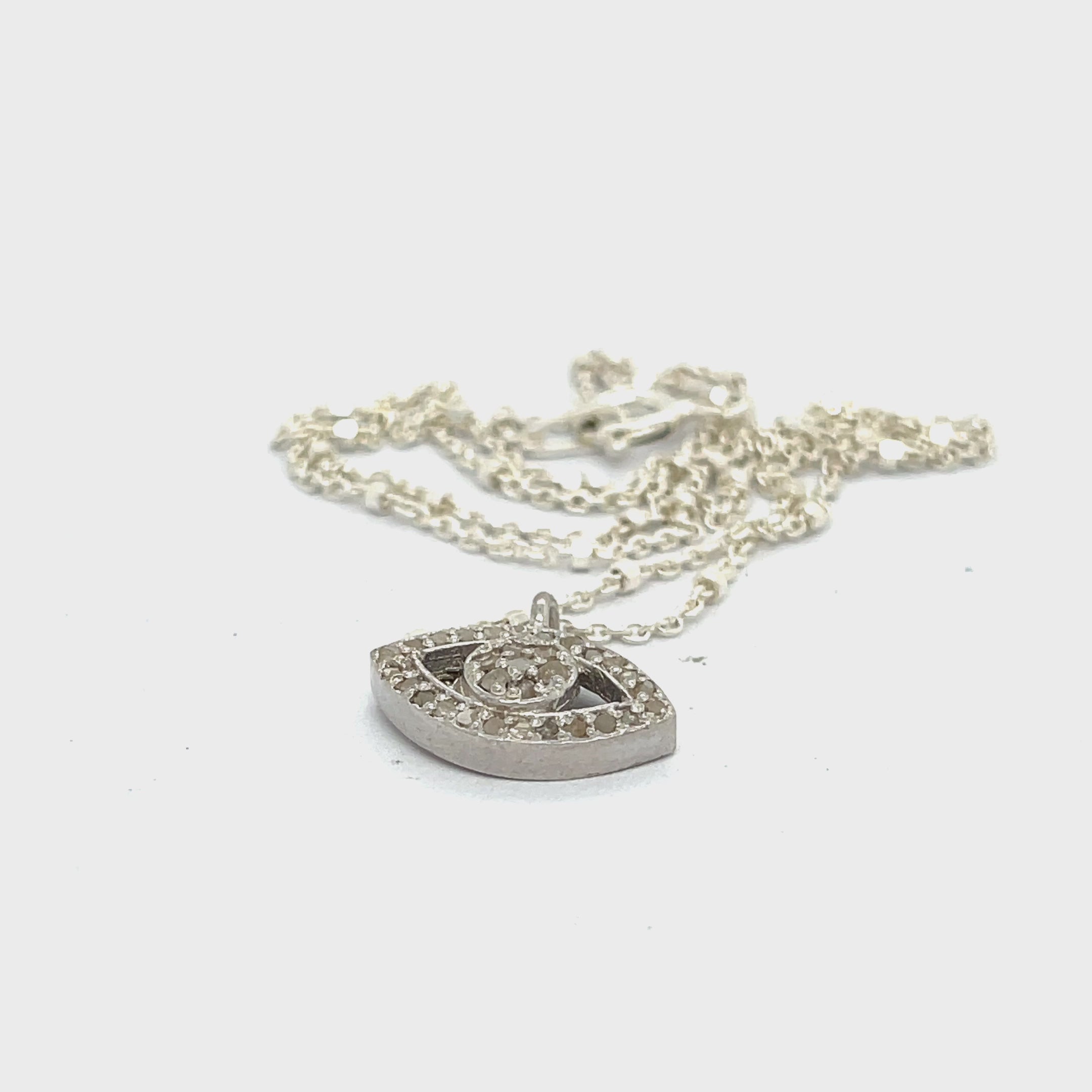 Close-up of diamond Evil Eye charm showing sparkle and silver details on a white background center overview video