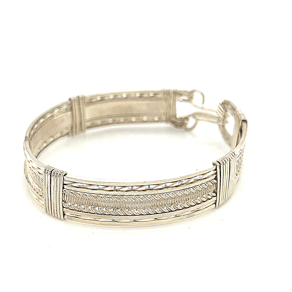 Handcrafted sterling silver wire-wrapped bangle with twisted and straight wire combination showing polished dome centerpiece, on a white background, front right angle view. video
